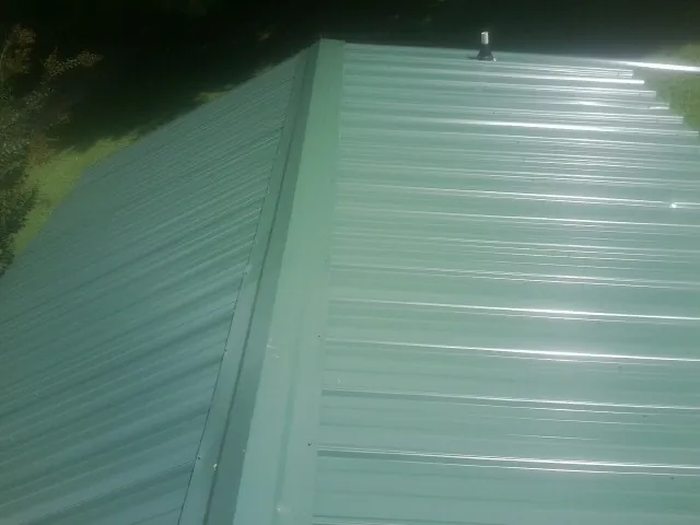 New green metal panels meeting at the ridge of a roof — Flat Roof Repair work by our crew in Mango