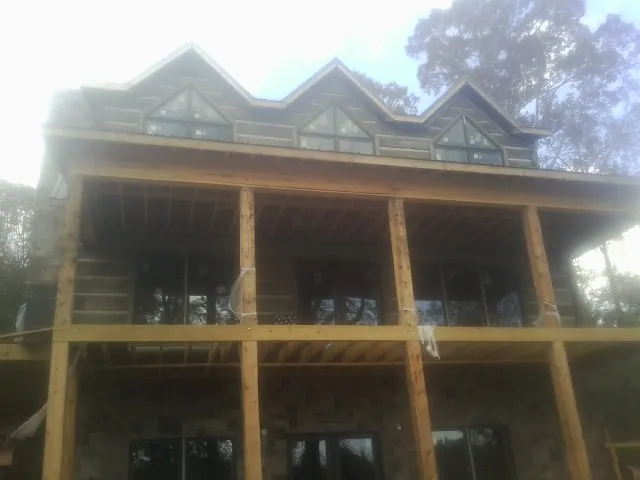 Dormers and porch framing on a large log home under construction — Roof Coating work by our crew in Mango