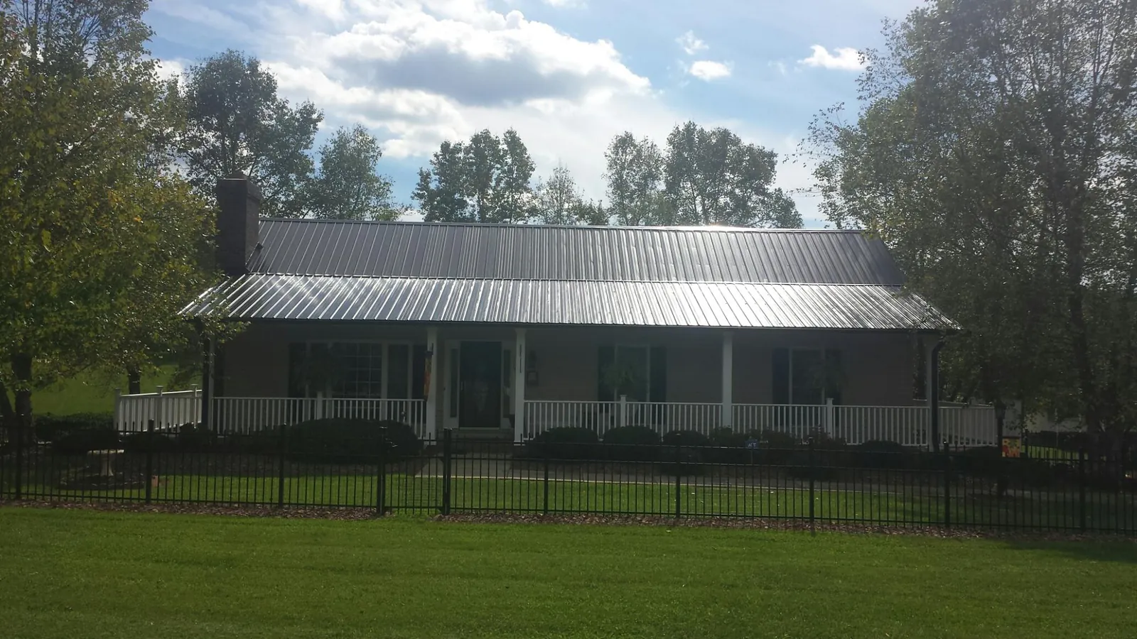 Gray metal roof on a brick ranch with a full width front porch — Gutter Guard Installation work by our crew in Mango